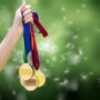 composite of hand holding medals over nature background